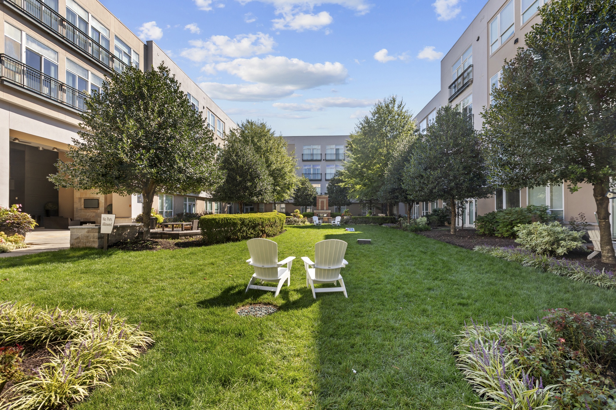 a courtyard with lawn chairs and trees in front of buildings